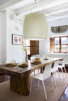 a dining room table with white chairs and a large light fixture hanging over it's head