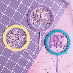 three happy birthday cake toppers on a pink and purple table with silver glitters