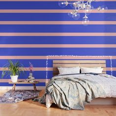 a bedroom with blue and pink striped wallpaper, a chandelier and a bed