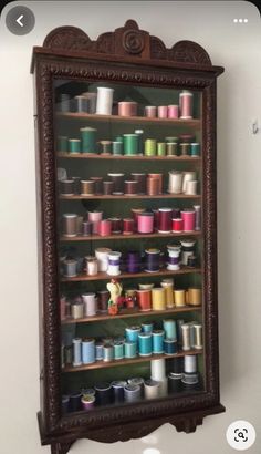 an old wooden shelf filled with lots of spools of thread on top of it