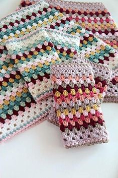 three crocheted dishcloths are sitting on a white surface, one is multicolored