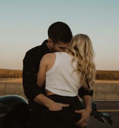 a man and woman embracing in front of a motorcycle