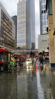 a city street filled with lots of traffic next to tall buildings on a rainy day