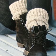 a pair of brown boots sitting on top of a white bench next to someone's legs