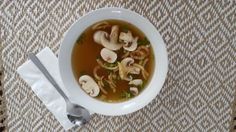 a white bowl filled with soup on top of a table next to a fork and napkin