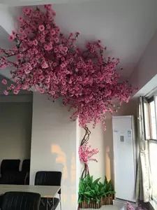 pink flowers are hanging from the ceiling in an empty room with black chairs and windows