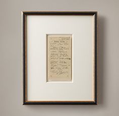 an old handwriting is framed in a black and white frame on the wall next to a vase