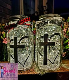 two mason jars with cross and heart decals on the lids are sitting next to each other