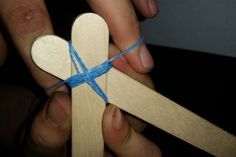 a person holding a wooden cross with blue string