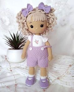 a crocheted doll standing next to a potted plant