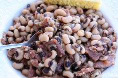 a white bowl filled with black eyed peas next to a cornbread on the side