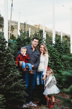 a man, woman and child standing in front of christmas trees at the tree farm