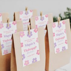 small brown bags with pink and purple flowers on them are hanging from clothes pins that read, thank you the magic's mother