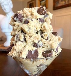 an ice cream sundae with chocolate chips in a glass bowl on a wooden table