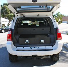 the back end of a white suv with its trunk open