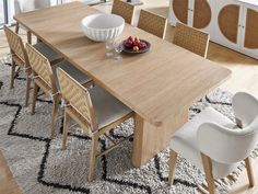 a dining room table with chairs and bowl of fruit on the plate next to it