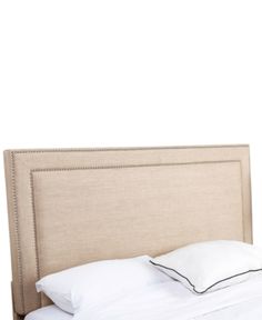 an upholstered headboard on a bed with white sheets and pillows