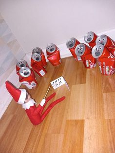 an elf is sitting on the floor next to some soda cans