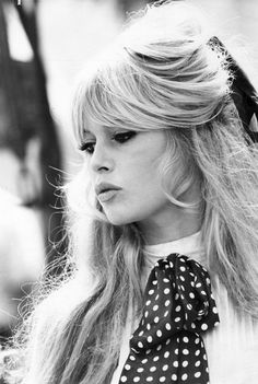 a woman with long blonde hair wearing a red and white polka dot bow around her neck