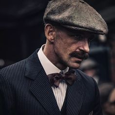 a man in a suit and bow tie wearing a hat with a moustache