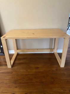 a wooden bench sitting on top of a hard wood floor next to a wall and window