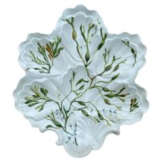 a white platter with green leaves and stems on it's rim, isolated against a white background