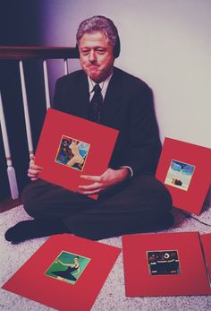 a man sitting on the floor holding up some red boxes with pictures in them,