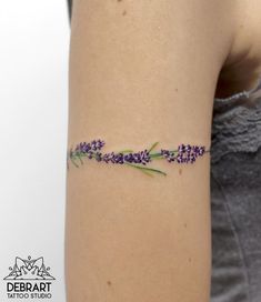 a woman with a tattoo on her arm has lavender flowers in the middle of it