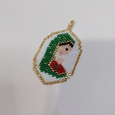 a beaded christmas ornament hanging from a gold chain on a white surface