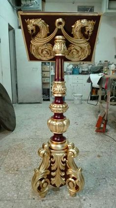 a gold and red clock sitting on top of a wooden stand in a room filled with tools