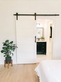 a bedroom with a bed, plant and sliding barn doors in the door to another room