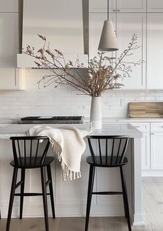 two black chairs sitting next to each other in a kitchen with white cabinets and counter tops