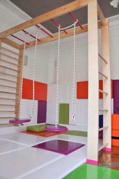 a room with various colored carpeted floors and wooden ladders hanging from the ceiling