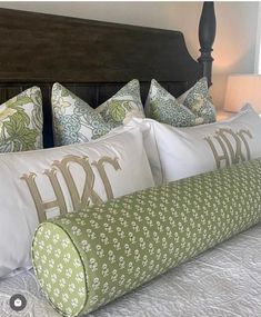 a bed with white and green pillows on it