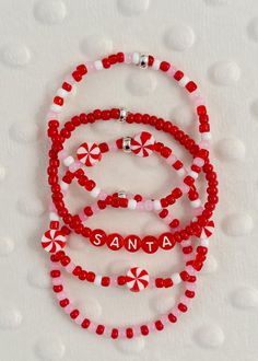 three red and white beaded bracelets with santa written on them