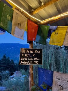 there are many flags hanging from the roof and some signs on the pole in front of them