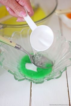 a person spooning liquid into a glass bowl with green and white stuff in it