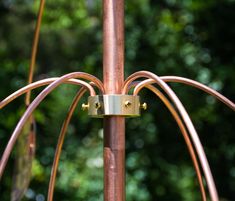 two copper wires connected to each other on top of a metal pole with trees in the background