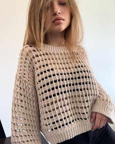 a woman sitting on a chair with her eyes closed wearing a knitted sweater and jeans