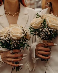 two women in white coats holding bouquets of roses and baby's breath buds