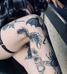 a woman with tattoos on her legs sitting next to a wall