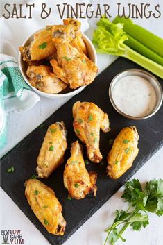 chicken wings with dipping sauce and celery on a black slate board next to it