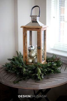 a wooden table topped with a lantern and christmas decorations