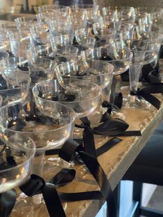 many empty wine glasses are lined up on a table with black ribbons and bows around them