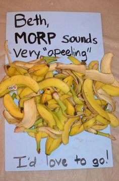 a pile of bananas sitting on top of a table next to a sign that says, morp sounds very appealing i'd love to go