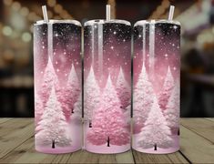 three pink christmas trees in front of a wooden table