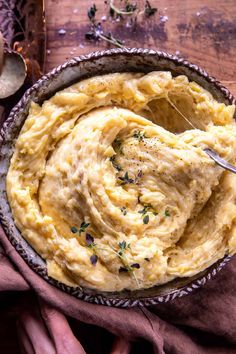 a bowl filled with mashed potatoes sitting on top of a table next to a spoon