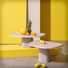 two white tables with pineapples on them in front of yellow and white walls