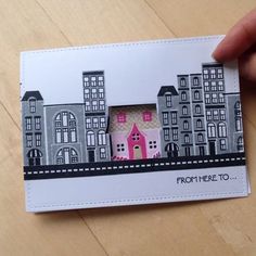 someone is holding up a small card with a pink house in the middle on it