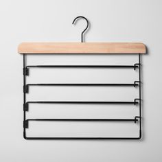 a wooden hanger with metal bars hanging from it's side on a white wall